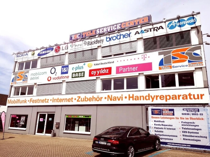 Fassade eines Tele Service Centers mit Logos von Mobilfunkanbietern und Handyreparatur-Hinweis.